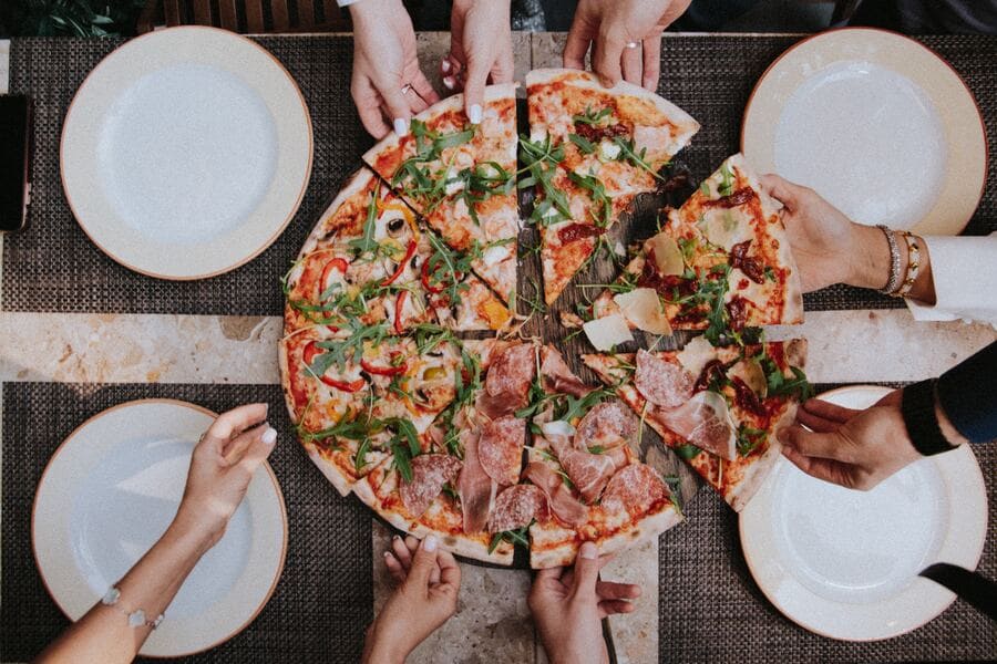 pessoas compartilham uma pizza meio a meio